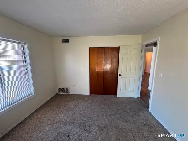 a view of an empty room with windows and closet