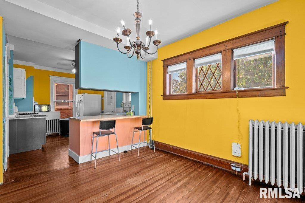 2105 15th Street Moline, IL 61265 - Photo 12 of 29 a dining room with wooden floor a chandelier a wooden table and chairs