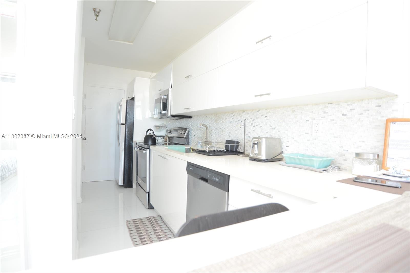 100 Lincoln Road, Unit 1605 Miami Beach, FL 33139 - Photo 7 of 20 a kitchen with stainless steel appliances kitchen island granite countertop a refrigerator and a sink
