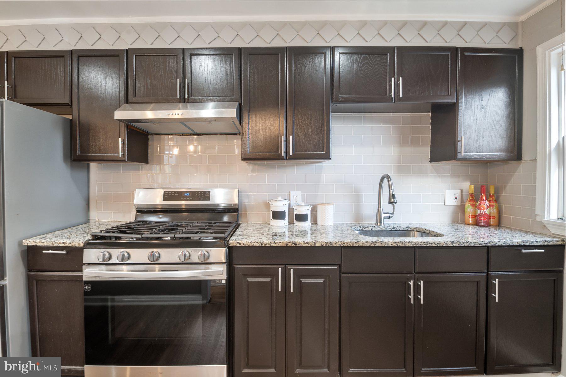 4801 Sinclair Lane Baltimore, MD 21206 - Photo 10 of 28 a kitchen with granite countertop stainless steel appliances a sink stove and cabinets