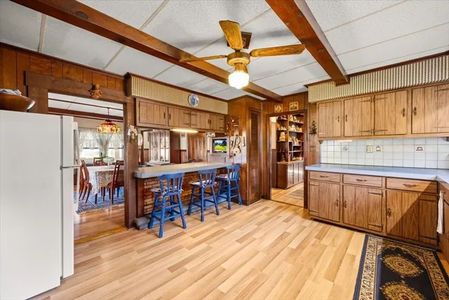 a kitchen with stainless steel appliances kitchen island granite countertop a refrigerator a stove a sink dishwasher and white cabinets with wooden floor