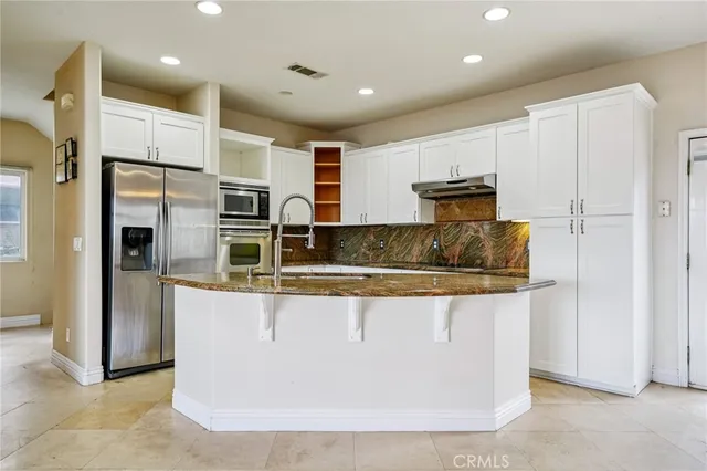 a kitchen with granite countertop white cabinets and stainless steel appliances