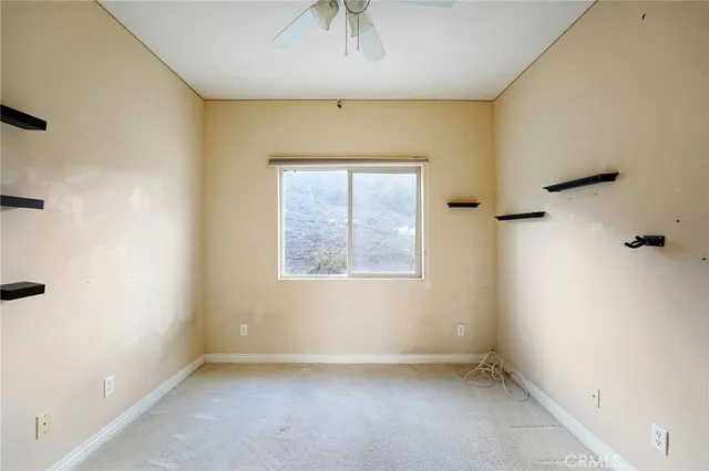 an empty room with a window and a fan