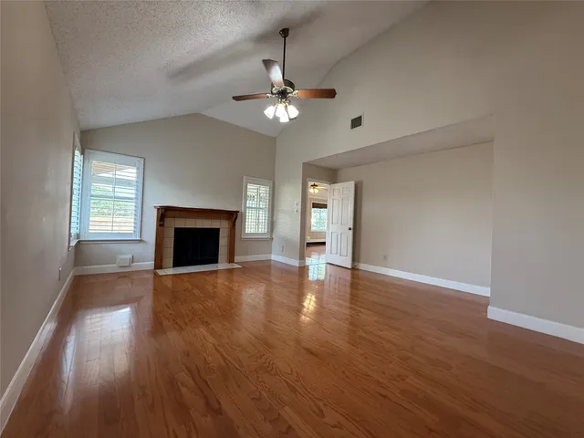 a view of an empty room with wooden floor fireplace and a window