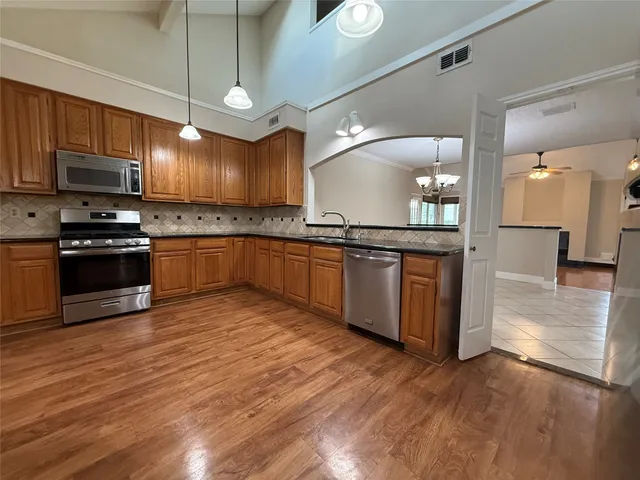 a kitchen with stainless steel appliances granite countertop wooden floors and white cabinets