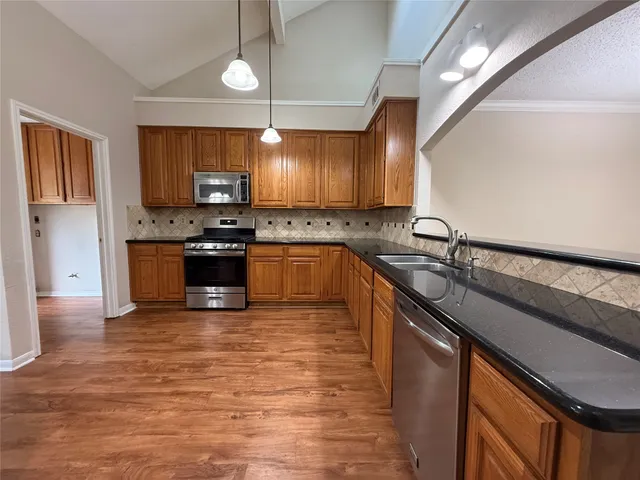 a kitchen with stainless steel appliances granite countertop a sink a stove and a wooden floors