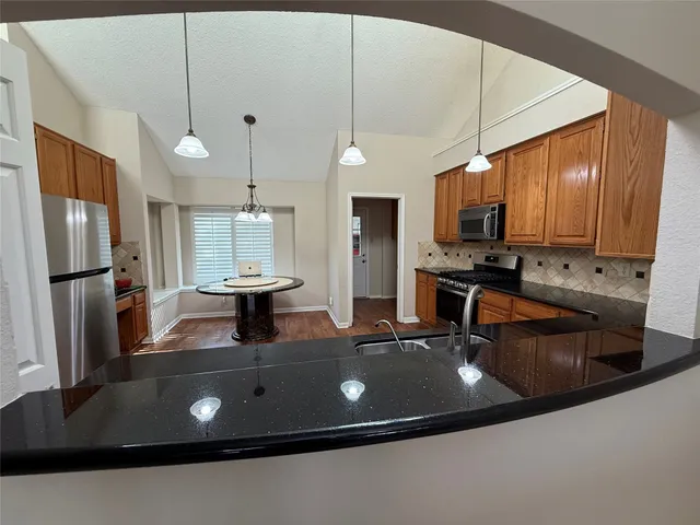 a kitchen with stainless steel appliances a sink a stove a refrigerator a center island and cabinets