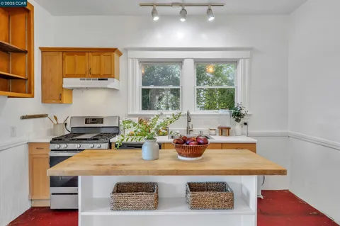 a kitchen with a stove a sink and a dining table with wooden floor