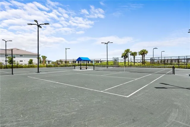 a view of a tennis ground with a table and chairs under an umbrella