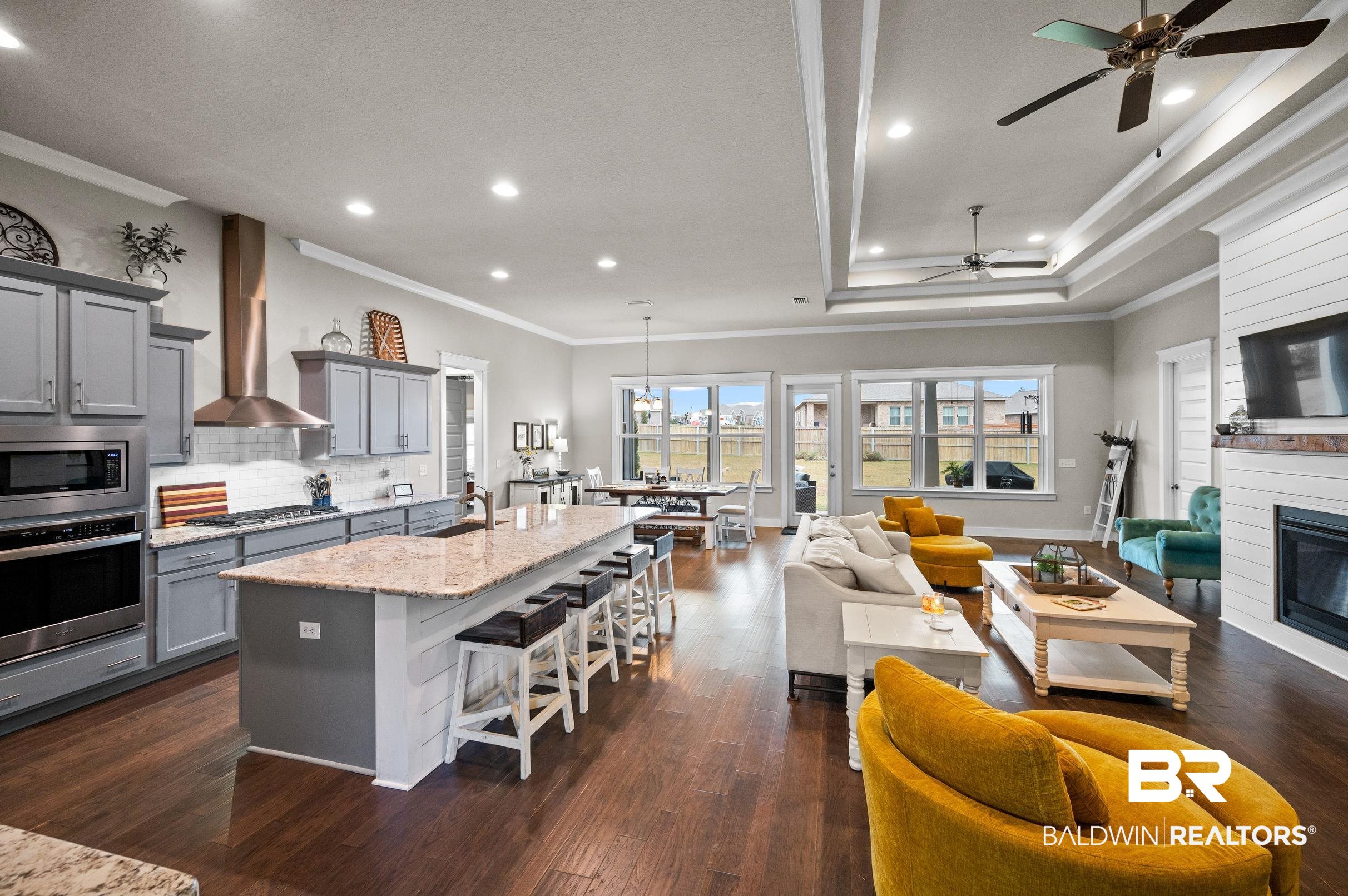 31355 Limpkin Street Daphne, AL 36527 - Photo 13 of 57 Kitchen featuring light stone countertops, appliances with stainless steel finishes, wall chimney exhaust hood, a large fireplace, and gray cabinets