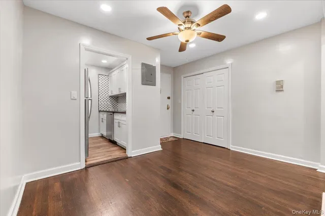 an empty room with wooden floor and a ceiling fan