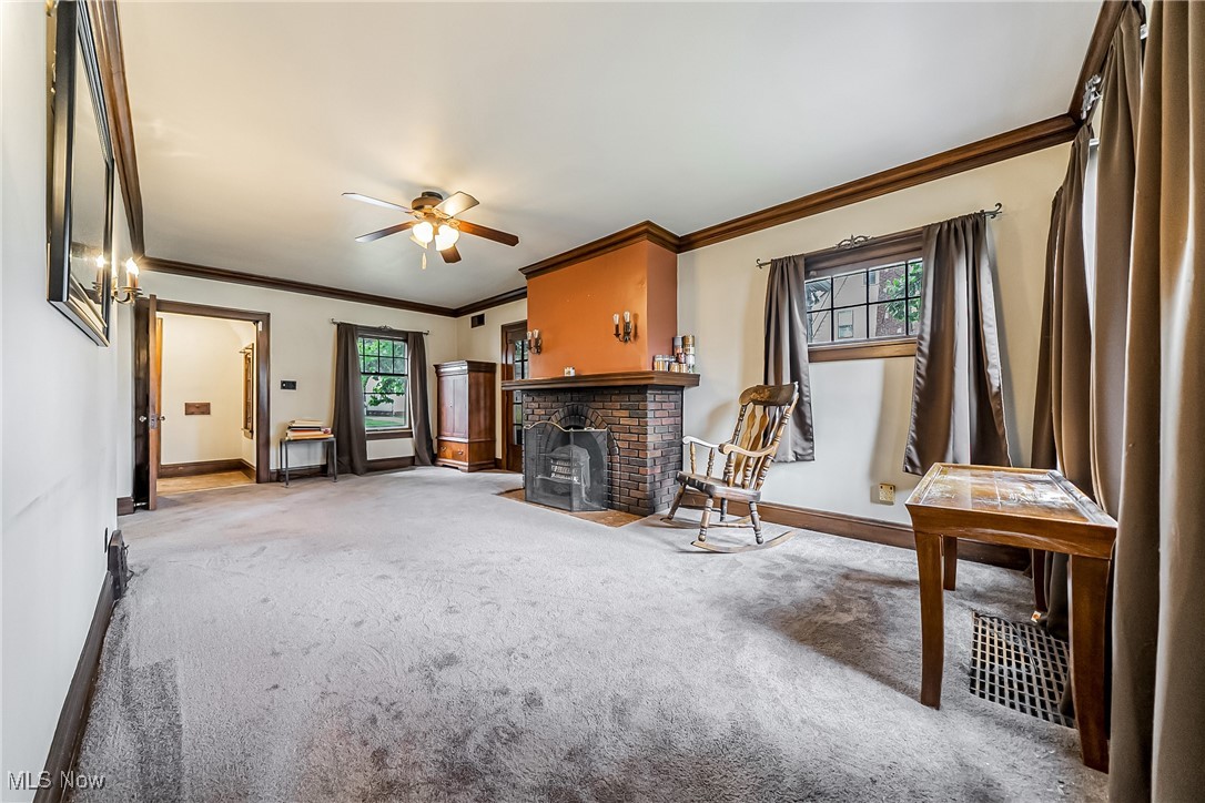 Carpeted living area with crown molding and a ceiling fan