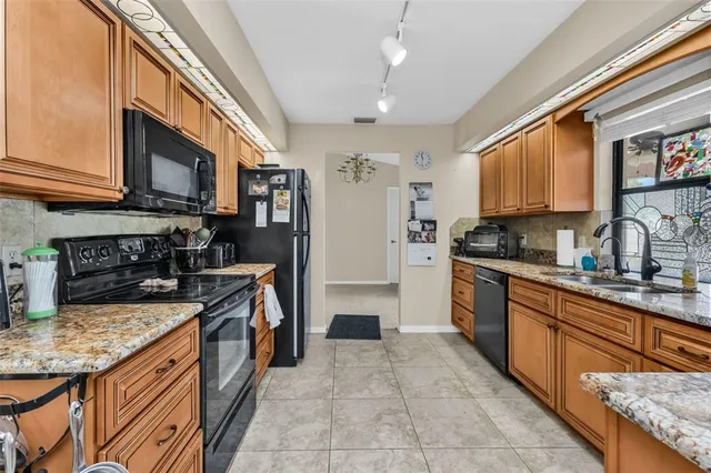 a kitchen with stainless steel appliances granite countertop a refrigerator a stove top oven a sink and dishwasher