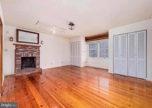a view of empty room with wooden floor and fireplace