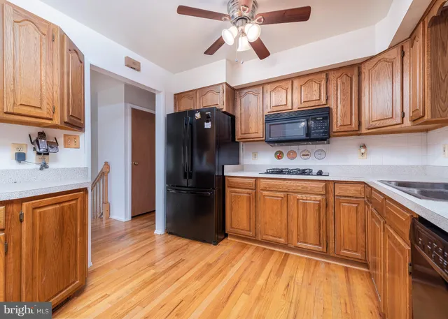 a kitchen with stainless steel appliances granite countertop a refrigerator a sink dishwasher and wooden cabinets with wooden floor