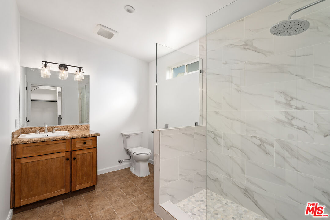 20850 Chase Street Winnetka, CA 91306 - Photo 20 of 25 a bathroom with a granite countertop sink a toilet and a shower