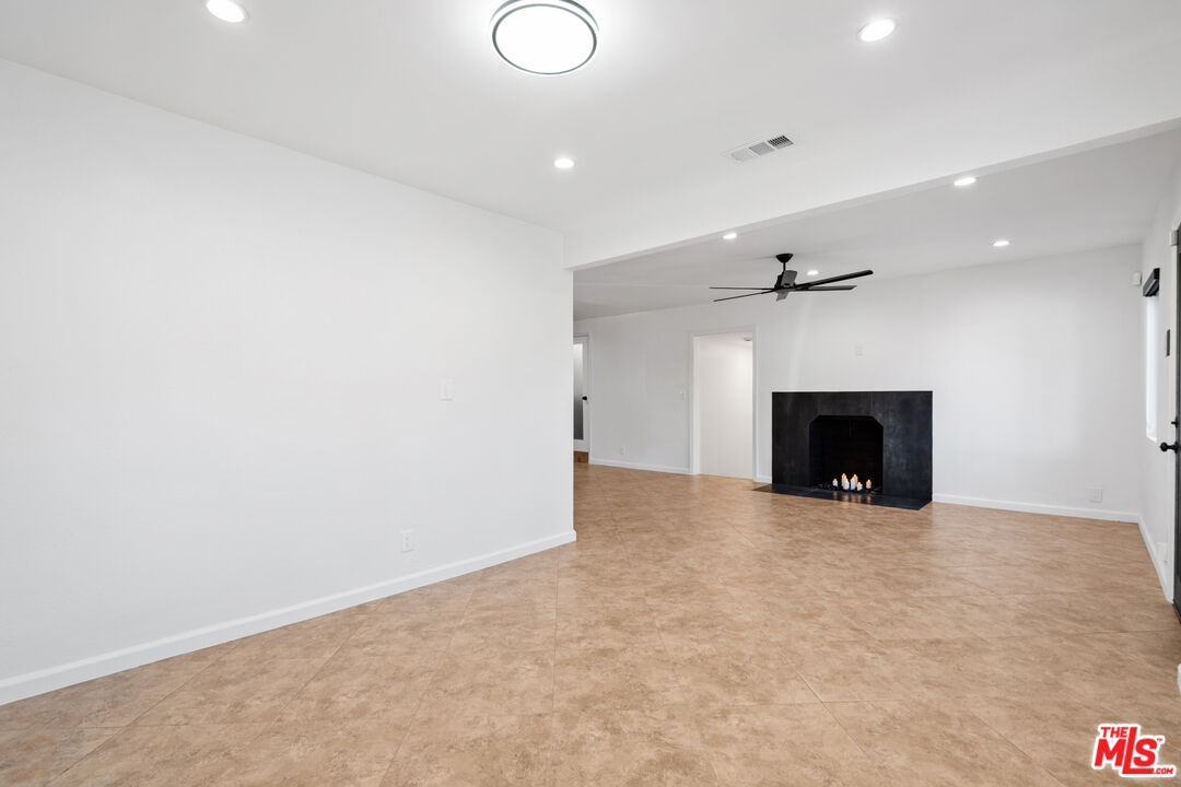 20850 Chase Street Winnetka, CA 91306 - Photo 7 of 25 an empty room with a fireplace and a chandelier fan