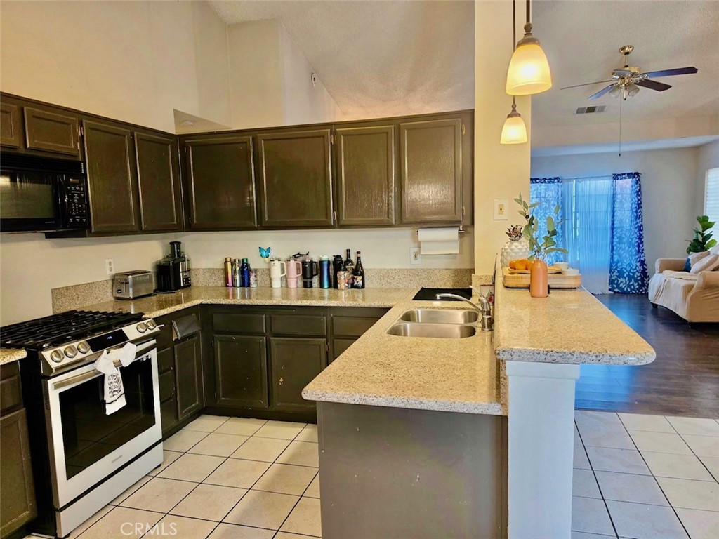 12966 Sundown Road Victorville, CA 92392 - Photo 6 of 20 a kitchen with a stove a sink and a refrigerator