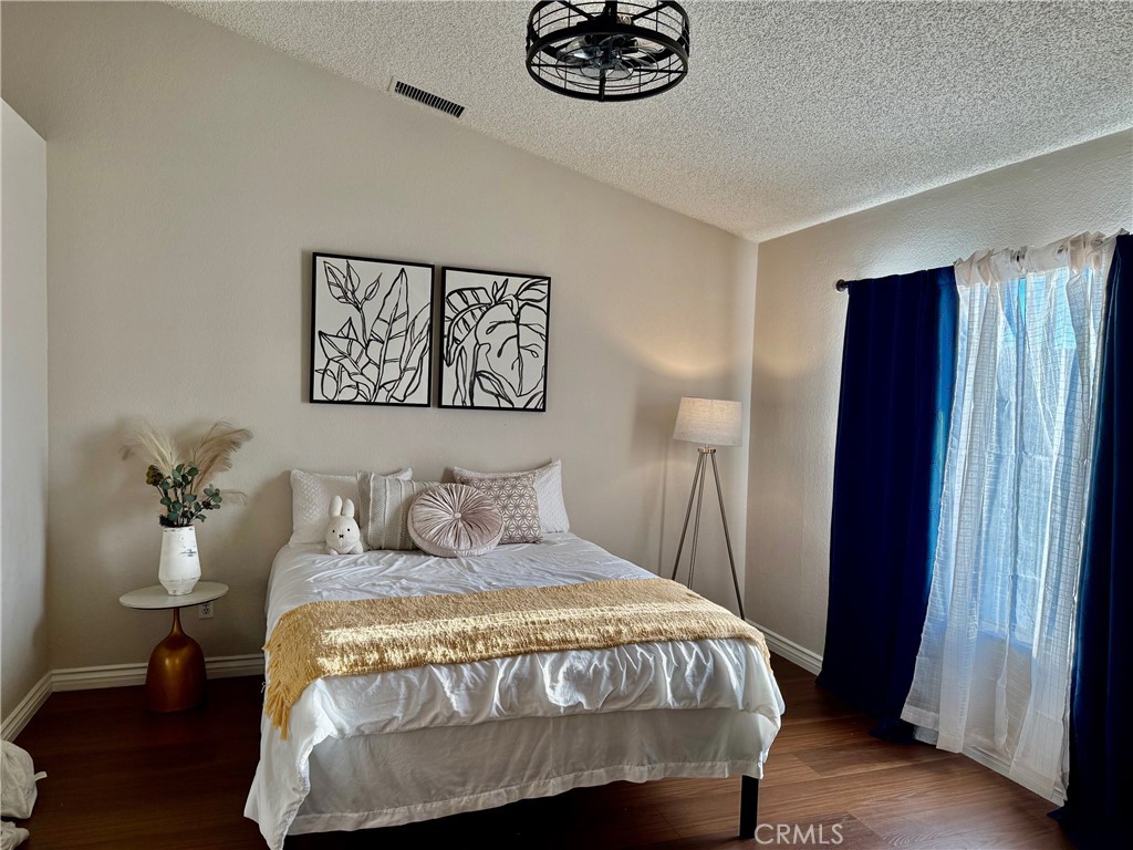 12966 Sundown Road Victorville, CA 92392 - Photo 8 of 20 a bedroom with a bed and a chandelier