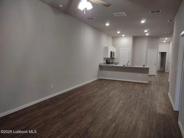 a view of a big room with wooden floor and a kitchen