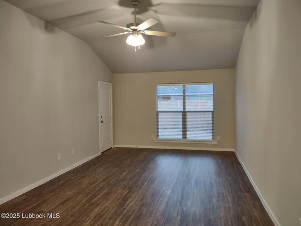 an empty room with wooden floor chandelier fan and windows