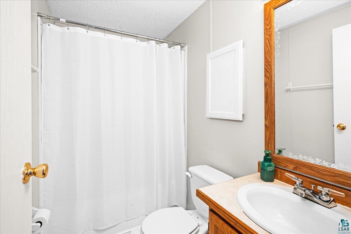 30 Ivy Drive Duluth, MN 55810 - Photo 12 of 21 Bathroom with vanity, a shower with curtain, a textured ceiling, and toilet