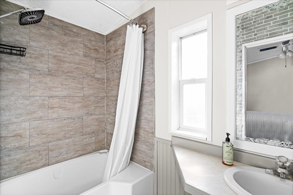 30 Ivy Drive Duluth, MN 55810 - Photo 17 of 21 Bathroom featuring a textured ceiling, shower / bath combo, sink, and a wealth of natural light