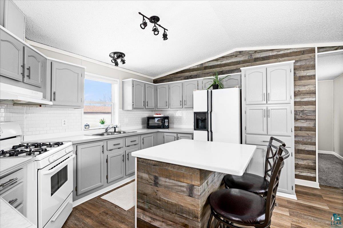 30 Ivy Drive Duluth, MN 55810 - Photo 6 of 21 Kitchen featuring white appliances, a textured ceiling, dark hardwood / wood-style flooring, and wooden walls