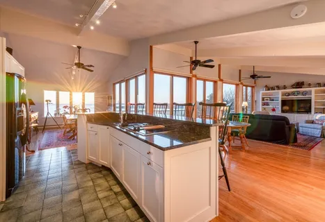 a kitchen with stainless steel appliances granite countertop a stove and a view of living room