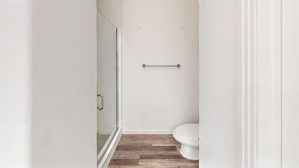 346 Buck Ridge Drive Frisco, TX 75068 - Photo 17 of 19 Full bathroom featuring light wood-style flooring, a shower stall, and a textured wall