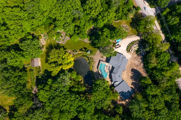 an aerial view of residential house with outdoor space and trees all around