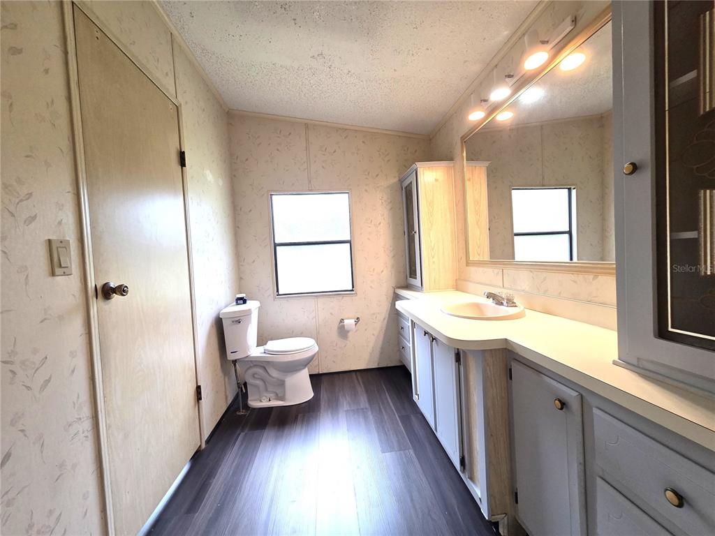 14822 Dilbeck Drive Spring Hill, FL 34610 - Photo 18 of 40 a spacious bathroom with a granite countertop sink toilet a large mirror a vanity and window