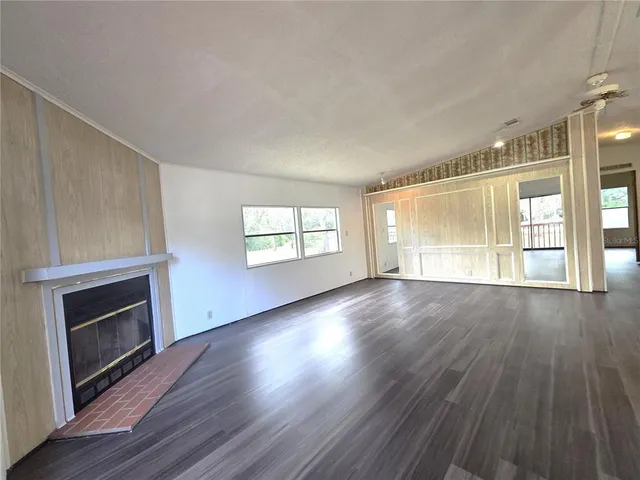 an empty room with wooden floor fireplace and windows