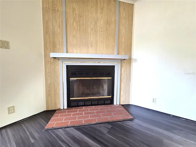 a view of an empty room with wooden floor fireplace and a window