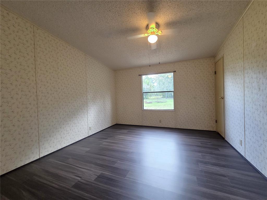 14822 Dilbeck Drive Spring Hill, FL 34610 - Photo 10 of 40 an empty room with wooden floor chandelier fan and windows