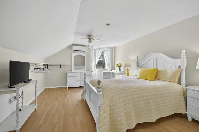 a bedroom with a bed and a flat tv screen on wall