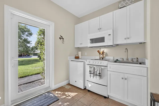 a kitchen with stainless steel appliances granite countertop a stove a sink and white cabinets with wooden floor