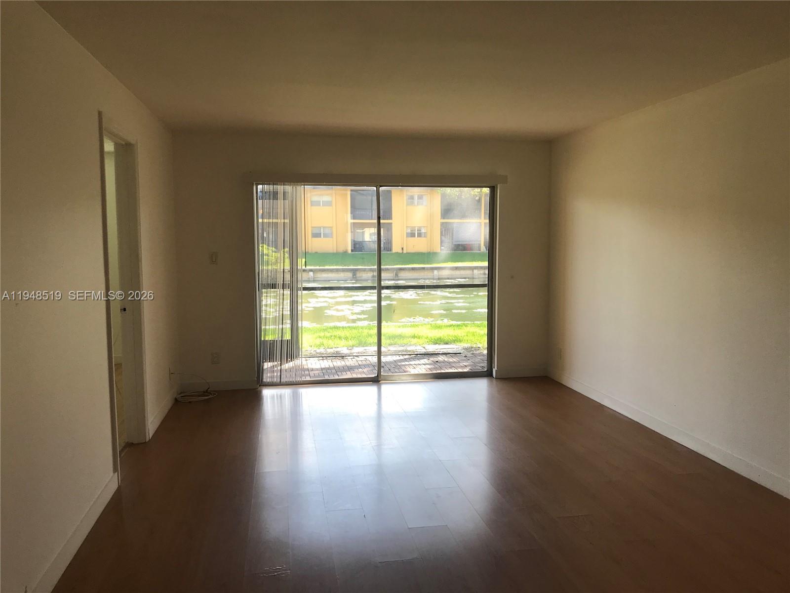 8040 North Colony Circle, Unit 101 Tamarac, FL 33321 - Photo 11 of 15 a view of an empty room with wooden floor and a window