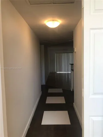 a view of a hallway with wooden floor and a window