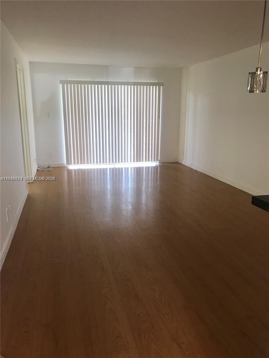 8040 North Colony Circle, Unit 101 Tamarac, FL 33321 - Photo 5 of 15 an empty room with wooden floor and windows