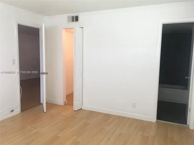 an empty room with wooden floor and closet