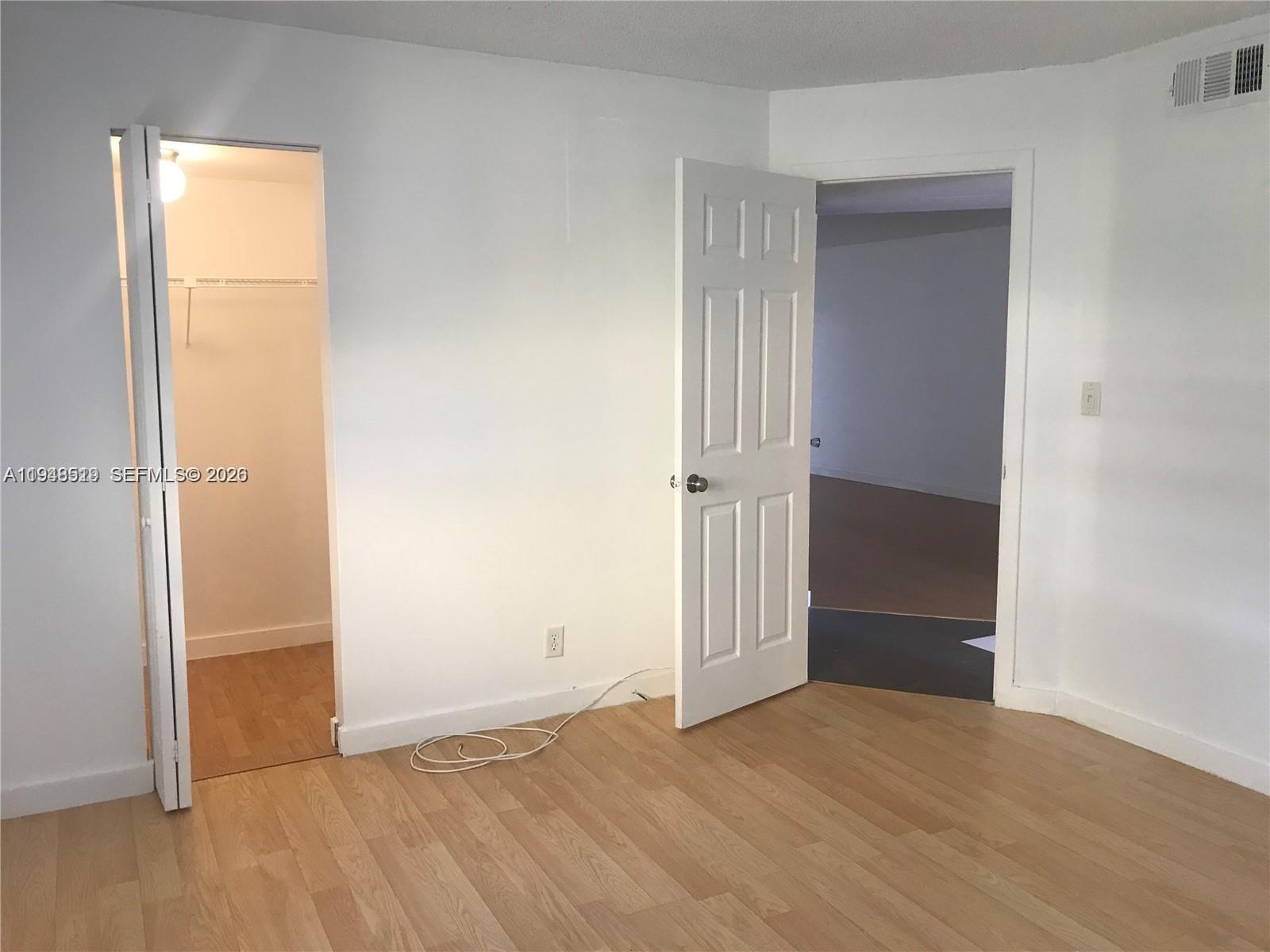 8040 North Colony Circle, Unit 101 Tamarac, FL 33321 - Photo 9 of 15 an empty room with wooden door and mirror