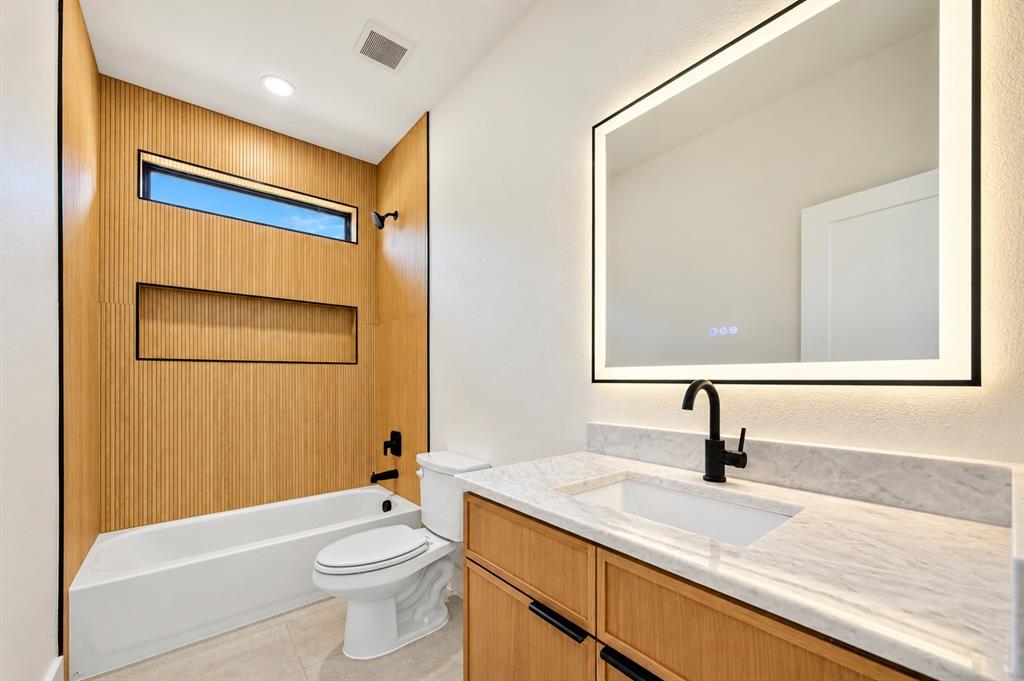 1632 West Wintergreen Road Lancaster, TX 75134 - Photo 19 of 30 Second Bathroom featuring wood paneling, a built-in shower niche, and a horizontal transom window