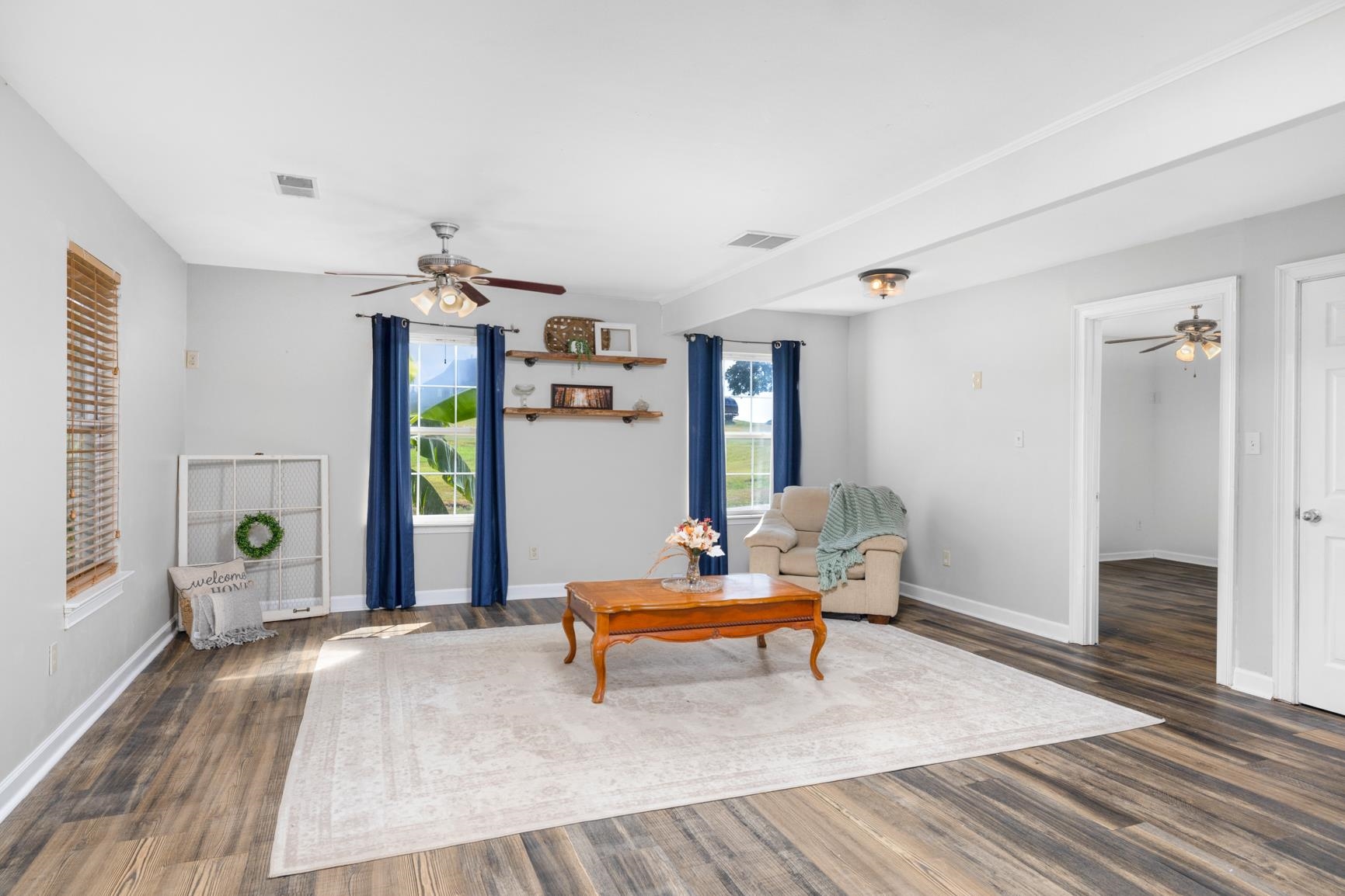 Wood-finish flooring, two windows with blinds, ceiling fan, recessed lighting, and wall-mounted shelving