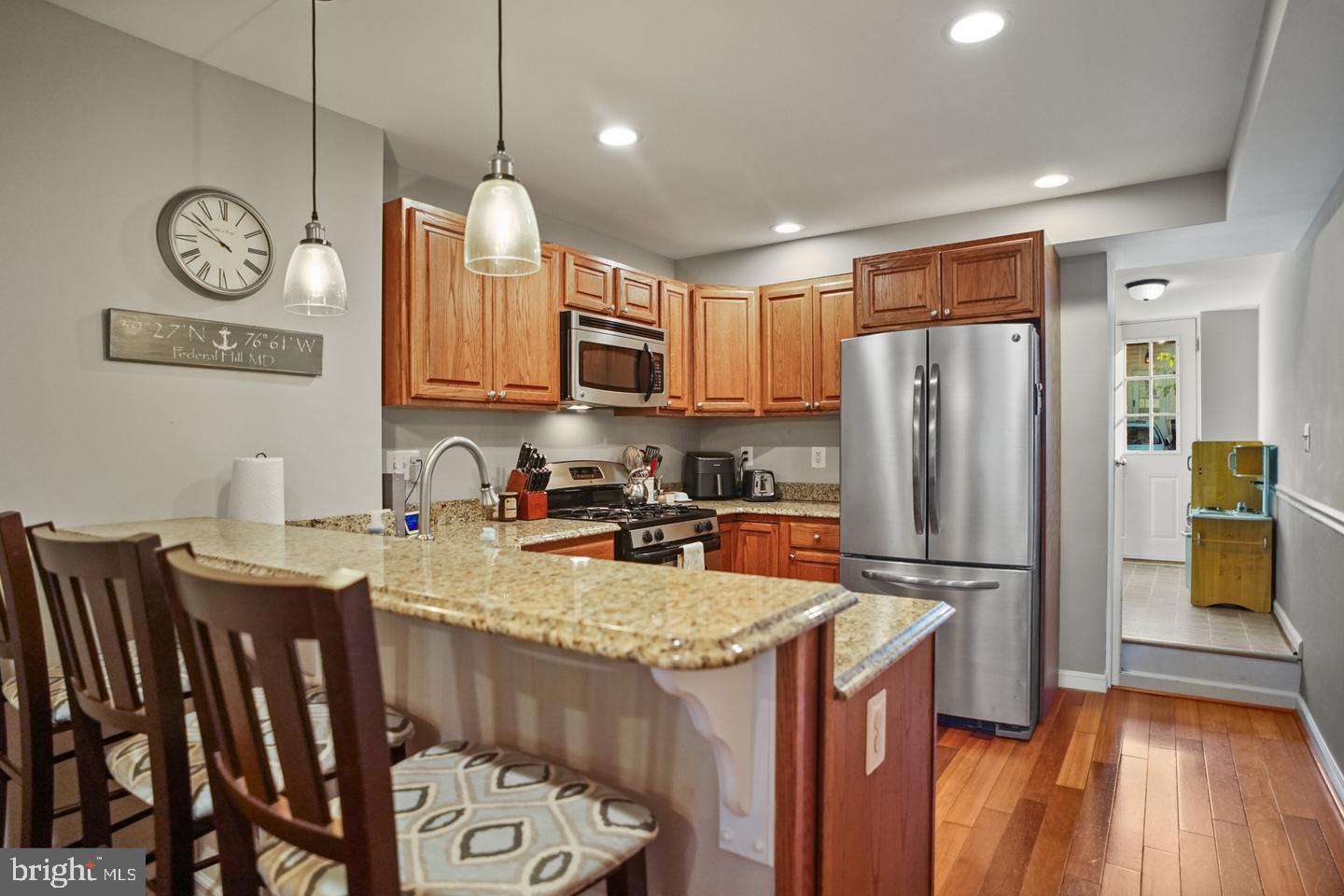 1421 Race Street Baltimore, MD 21230 - Photo 6 of 16 a kitchen with a refrigerator a stove a sink and a dining table with wooden floor