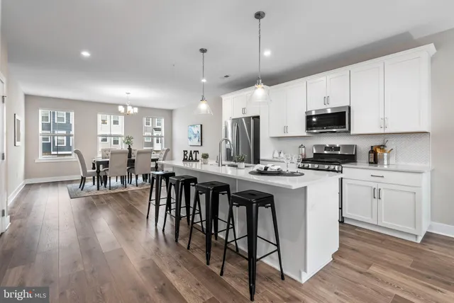 a kitchen with stainless steel appliances granite countertop a stove a sink a dining table and chairs with wooden floor