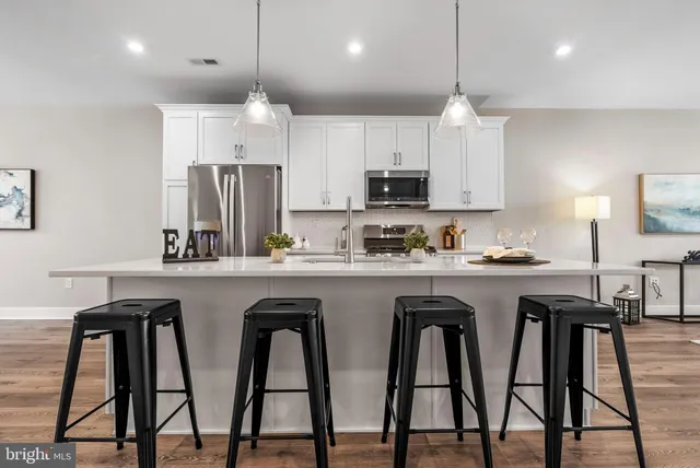 a kitchen with white cabinets and chairs