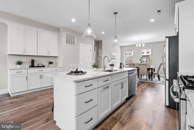 a kitchen with white cabinets stainless steel appliances and wooden floor