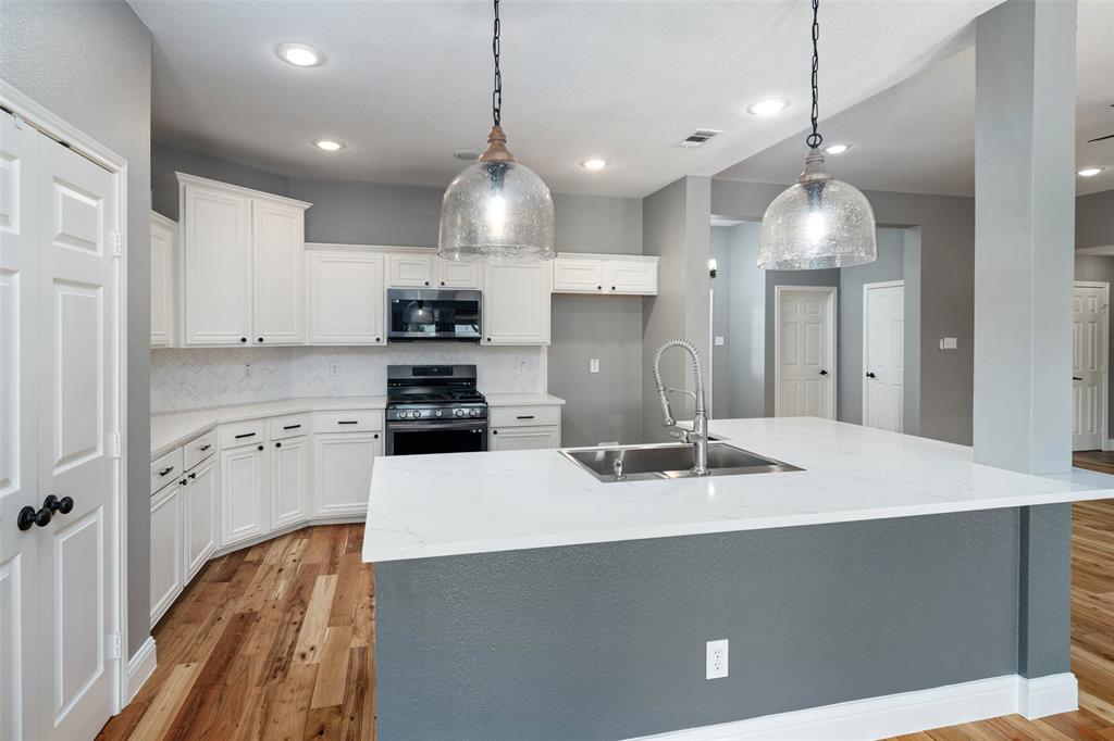 1019 Vaughan Lane Tioga, TX 76271 - Photo 9 of 40 Kitchen featuring white cabinetry, wood-finish flooring, recessed lighting, and a kitchen island with a double basin sink and a high-arc faucet