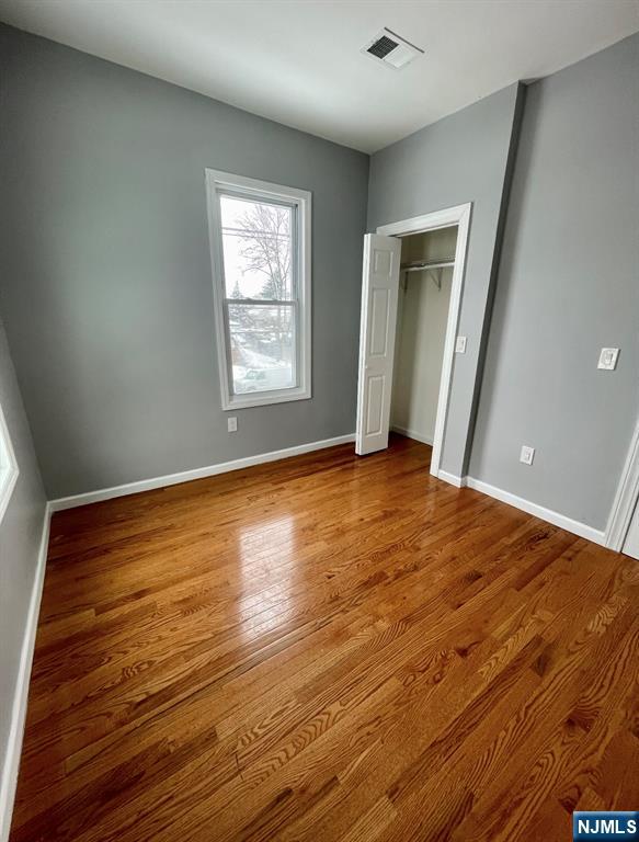 345 Kaplan Avenue, Unit 2 Hackensack, NJ 07601 - Photo 3 of 14 a view of an empty room with wooden floor and a window